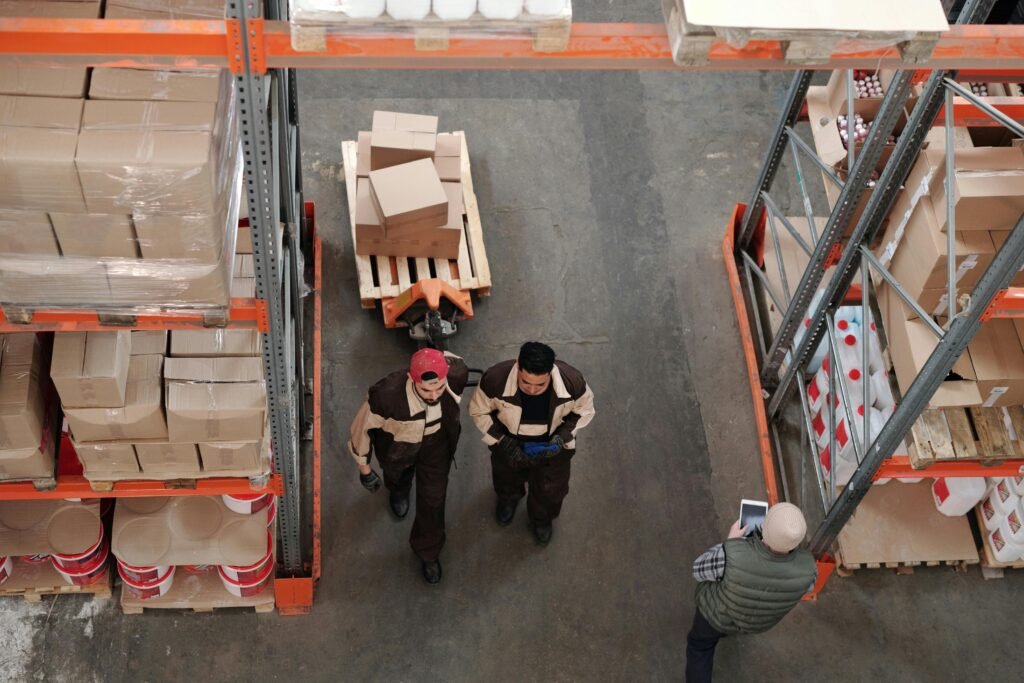 High angle view of warehouse workers organizing and preparing shipments with boxes and pallets.