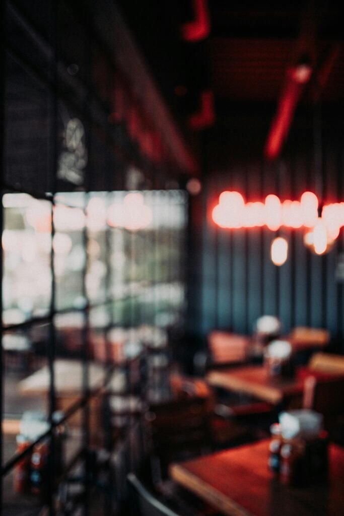 Cozy restaurant interior featuring modern furniture, blurred neon lights, and window views.