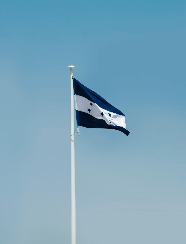 Honduras national flag waving proudly against a clear blue sky in Tegucigalpa.