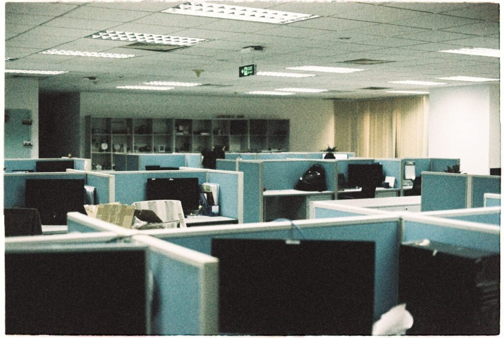 Spacious office floor with rows of empty cubicles and computer monitors.